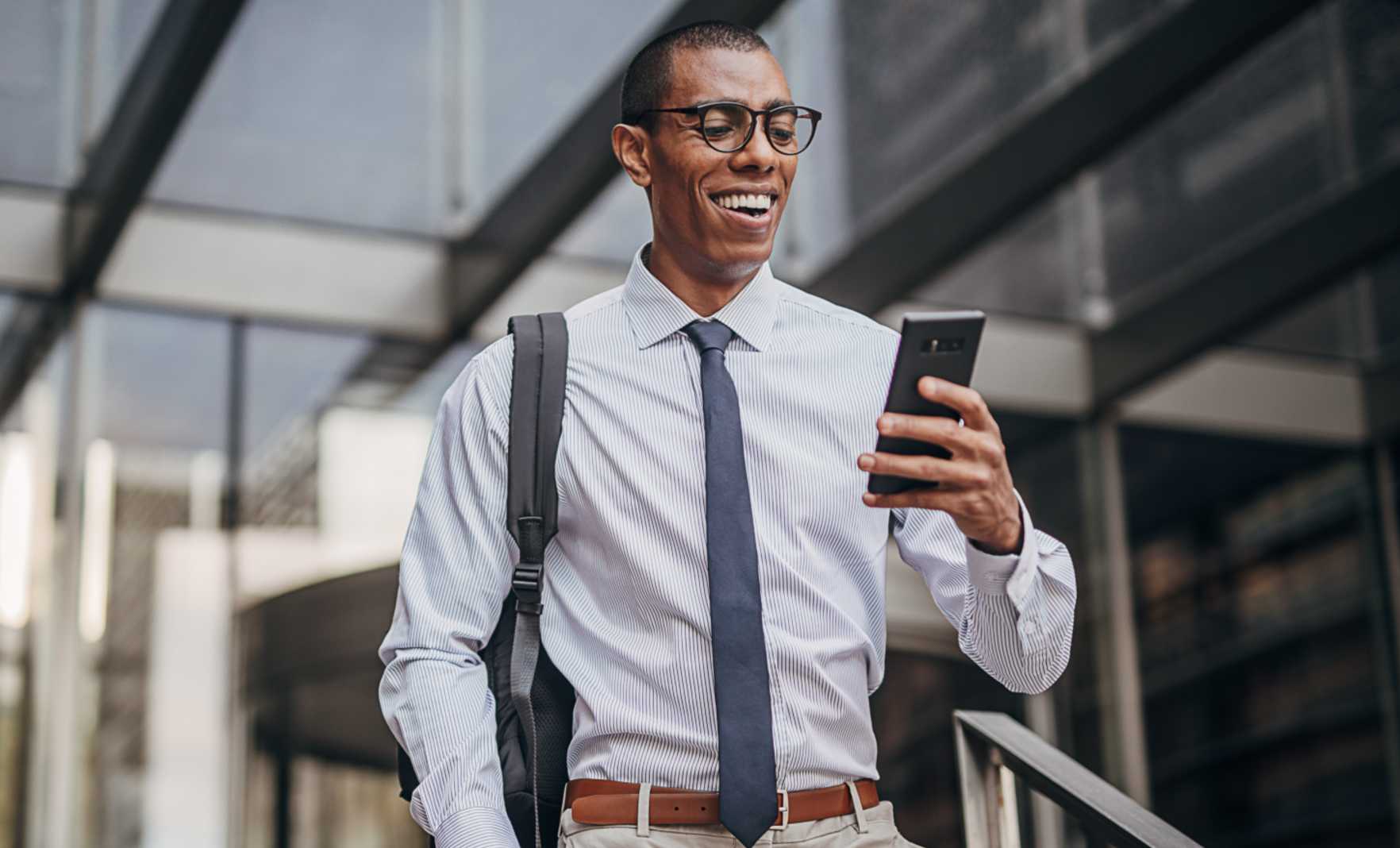Professional man walking outside smiling at phone