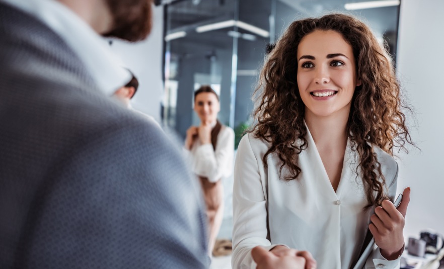 Professional woman shaking man's hand in an office