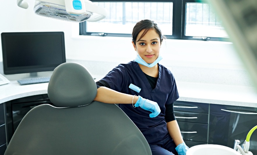 Young female dentist in scrubs wearing gloves in dental room