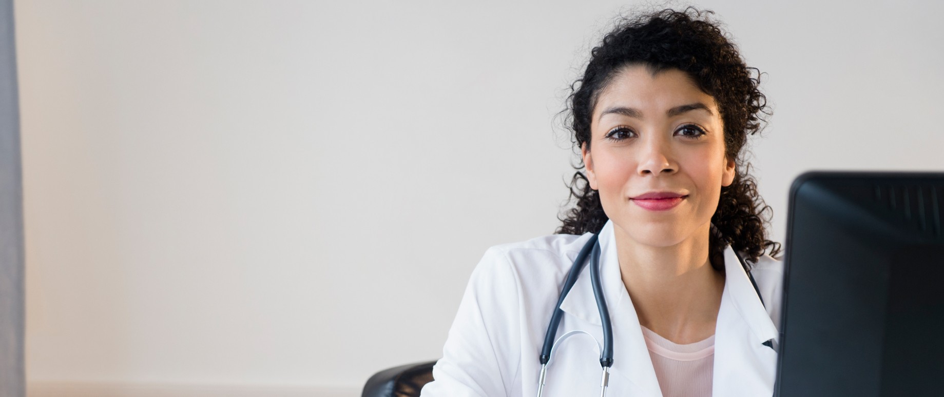 Female doctor sitting at desk wearing a white coat