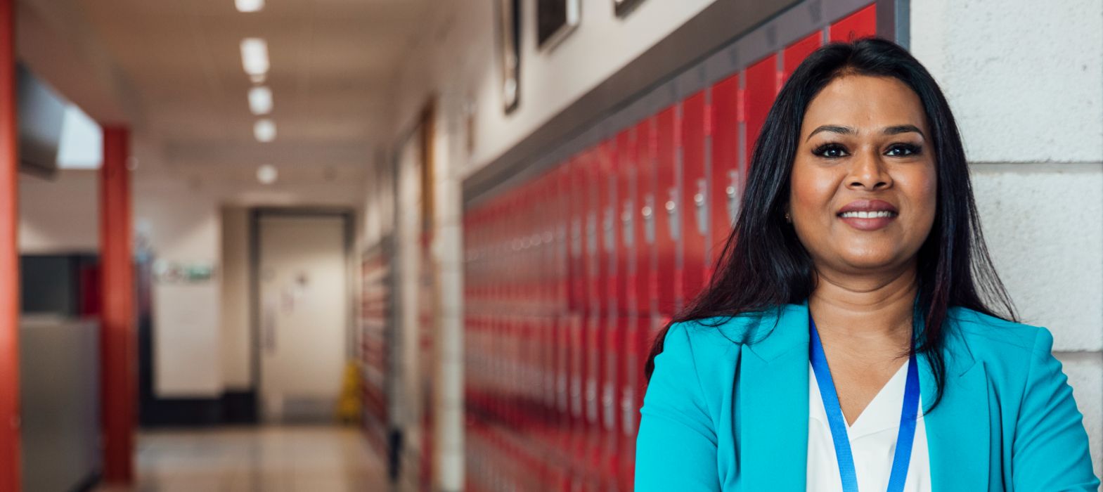 Female teacher standing in corridor in front of lockers