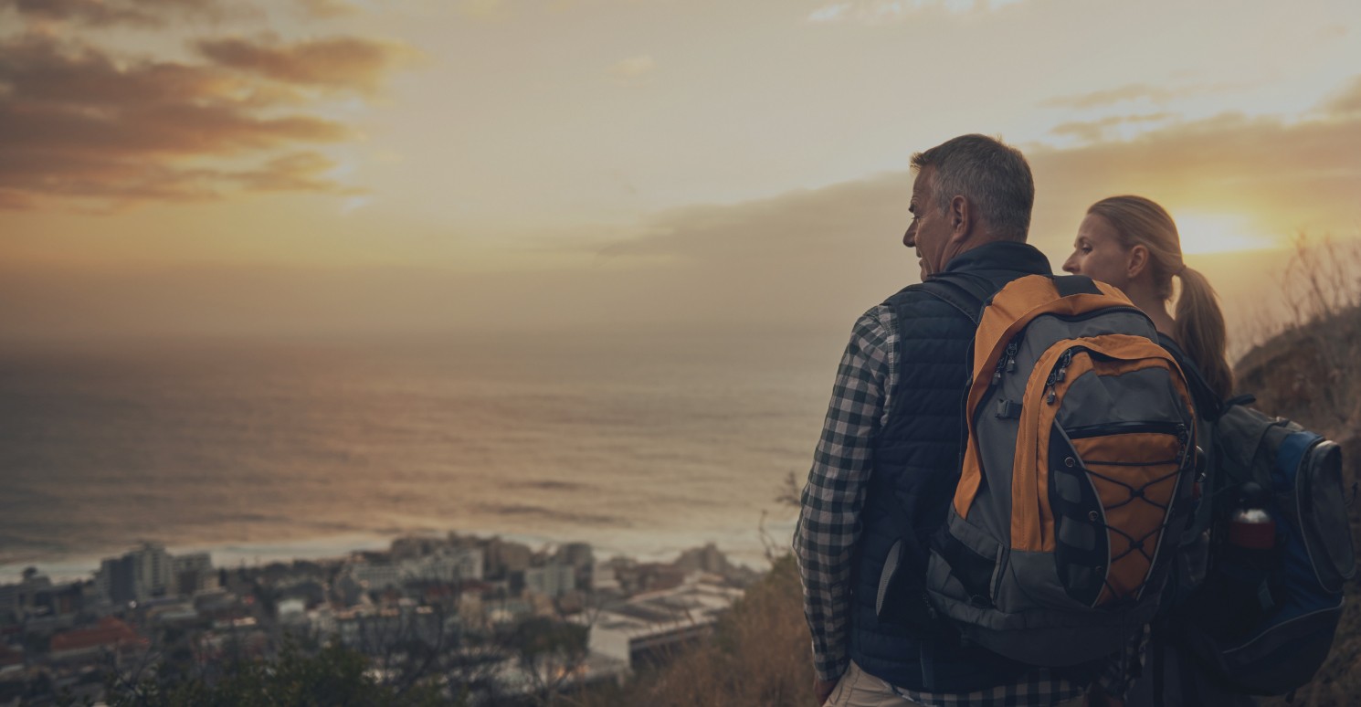 Couple at the top of hill looking out over town and sea while the sun sets