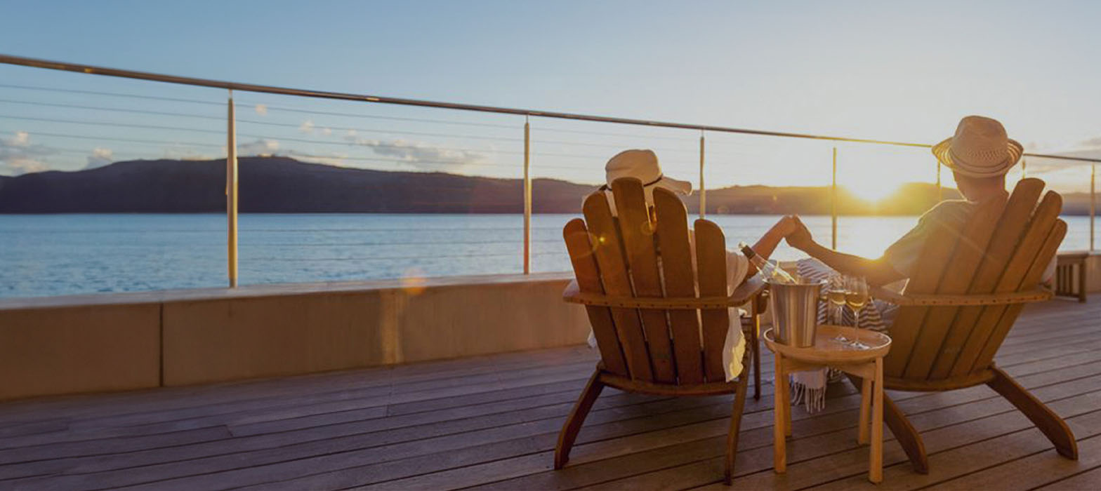 Mature couple in deckchairs looking at sunset