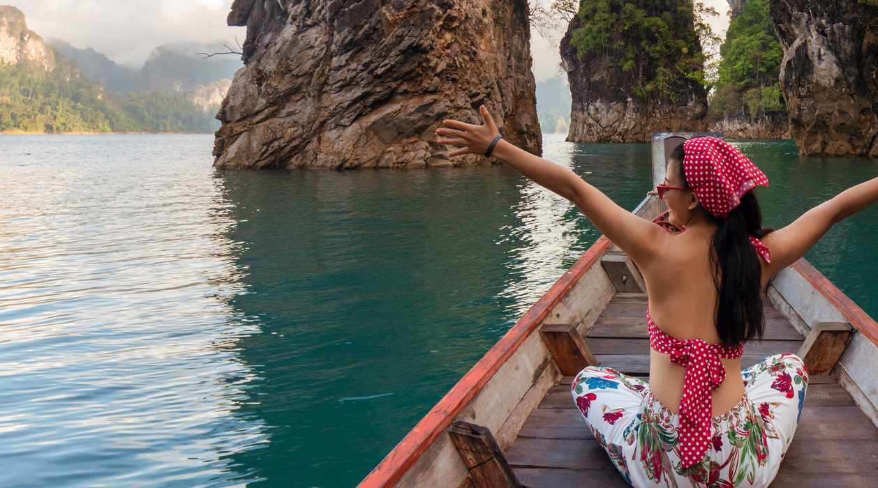 Woman sitting on boat on lake with open arms