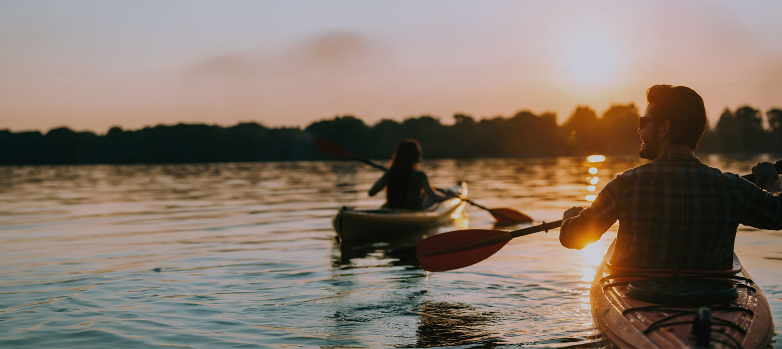 Younger couple in canoe boats in front of sunset