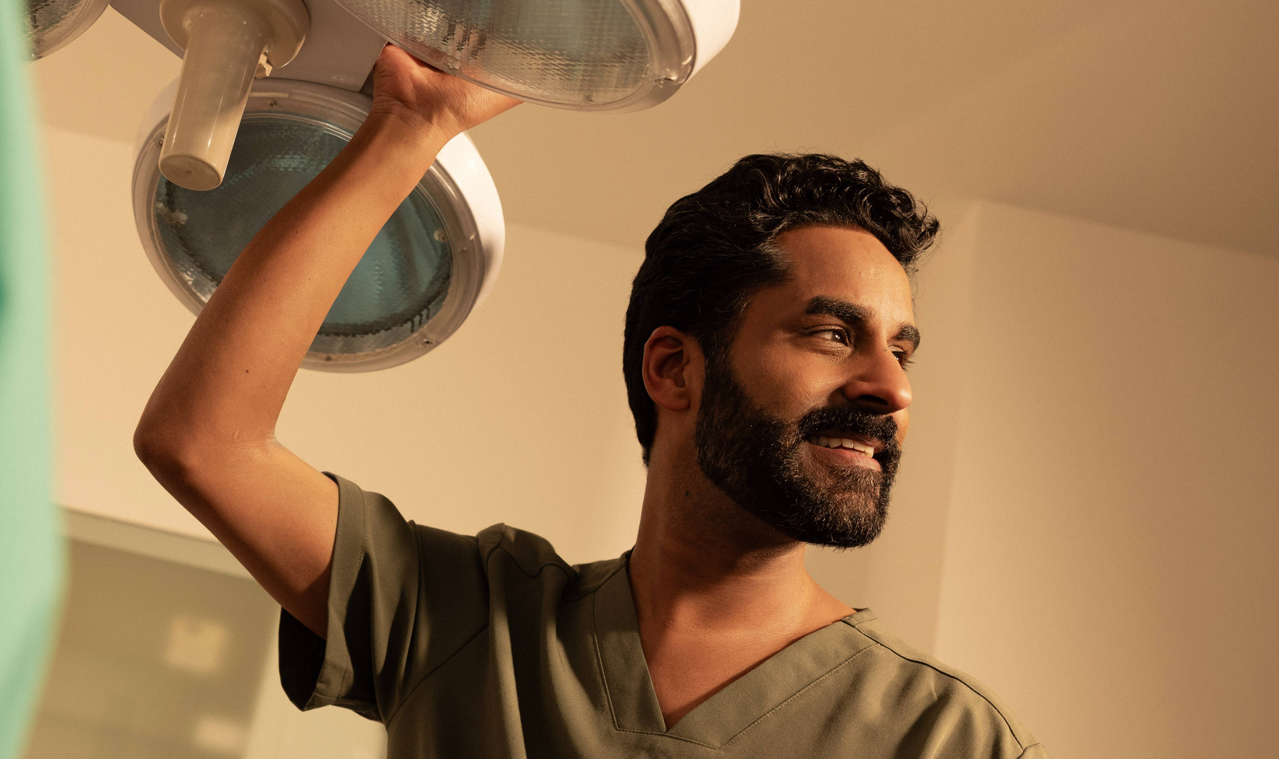 Male dentist adjusting equipment