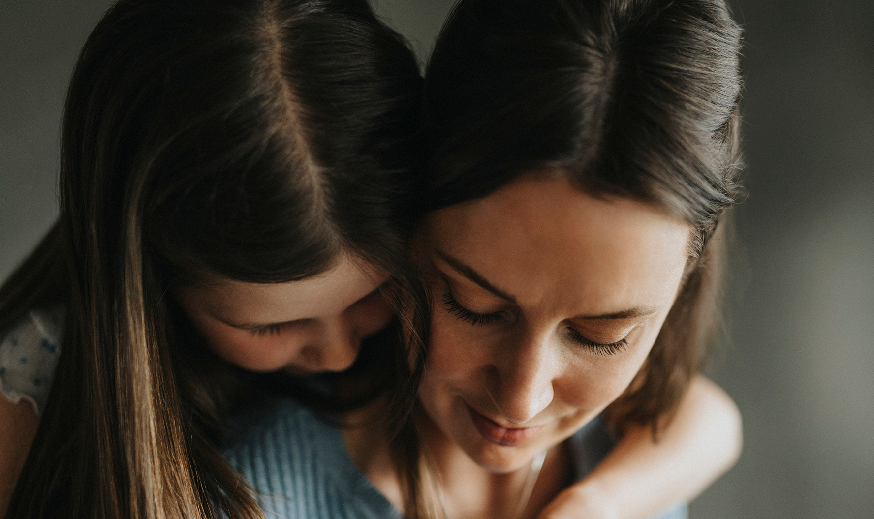 Daughter hugs mother from behind